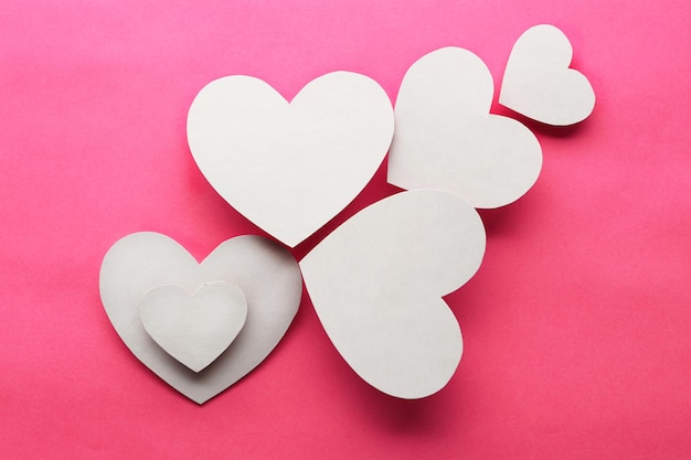 White paper hearts on pink background