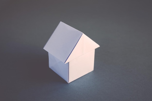 Белая бумага дом оригами, изолированные на сером фоне