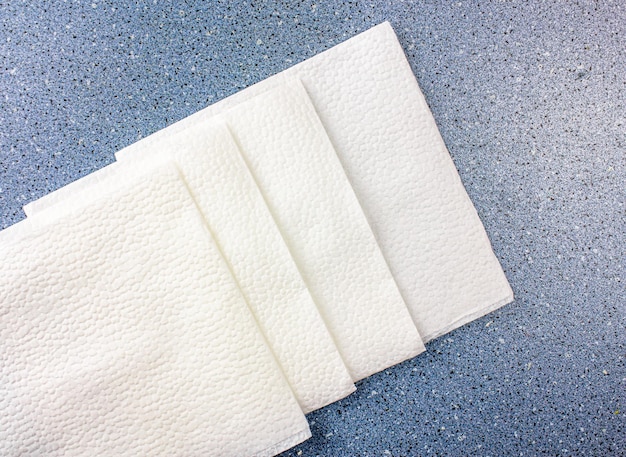 White paper napkins for table settingSoft white square napkins on a blue table backgroundClean paper napkins for personal hygiene