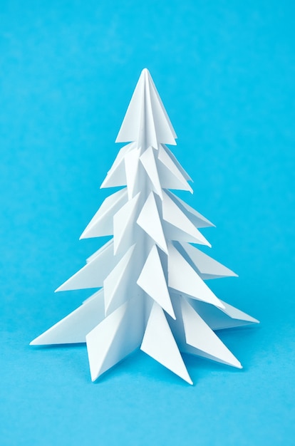 White paper origami Christmas tree on blue