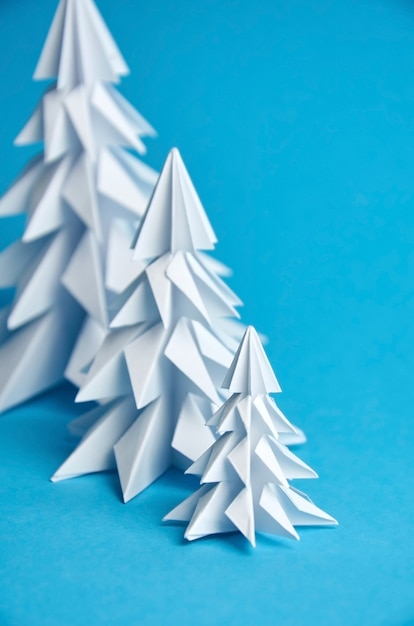 White paper origami Christmas trees on blue