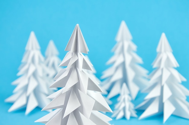 White paper origami christmas trees composition on blue