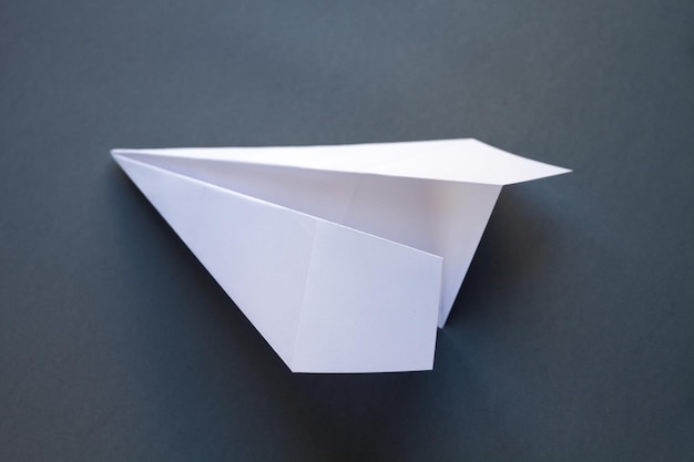 White paper plane origami isolated on a grey background