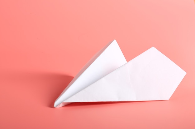 White paper plane on a pink background