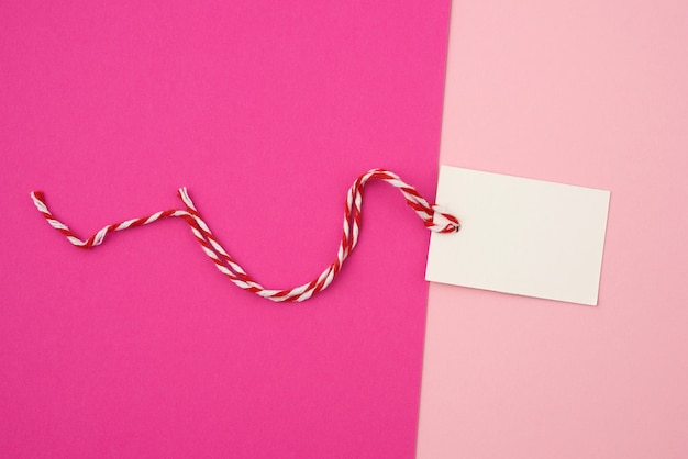 White paper rectangular tag on a rope on a colored background