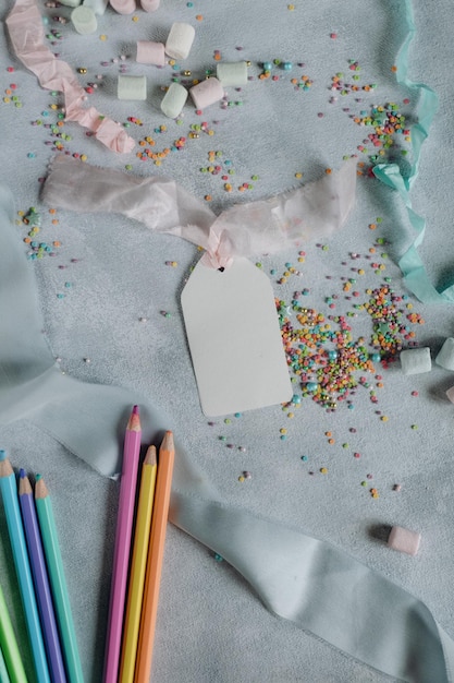 white paper sheet mockup on a gray background with pencils and colored confetti, tag mockup for a gi