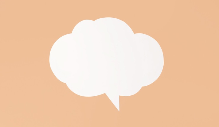 Photo white paper speech bubble sits on peach background the bubble is shaped like cloud and has single