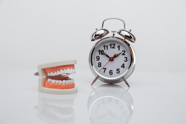 White paper tooth with alarm clock on blue