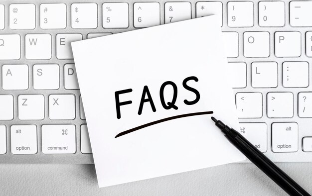White paper with text FAQS lying on the keyboard