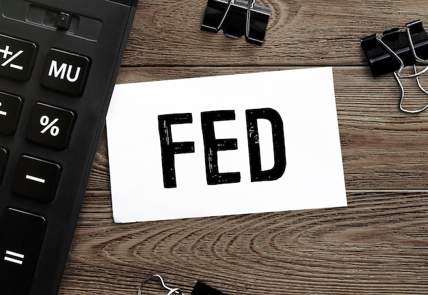 木の表面に文房具とテキスト FED が記載された白い紙