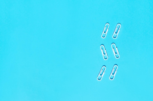 White paperclips on blue background Education concept