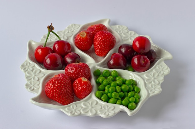 White partitioned dish with strawberries, green pea and cherries o