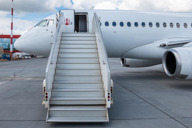 White passenger aircraft with a boarding steps on the airport\
apron