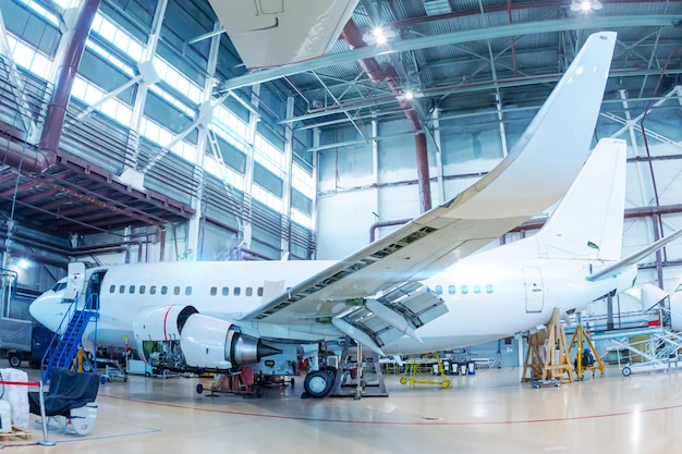 White passenger airliner in the hangar Aircraft checking mechanical systems for flight operations