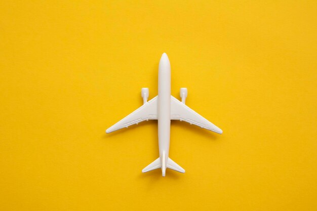 White passenger airplane on a summer yellow background. Travel and vacation background.