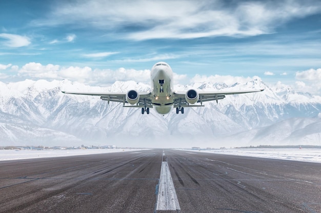 White passenger plane take off airport runway at winter on background of high snow capped mountains