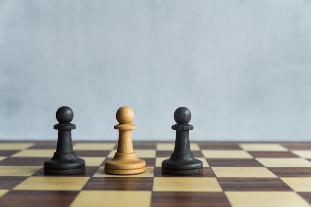 A white pawn surrounded by two black pawns