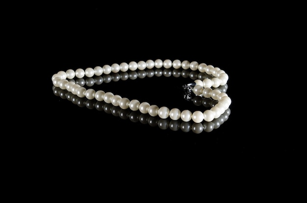 White pearls on black background with reflection