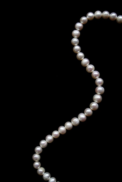 Photo white pearls on the black silk as background