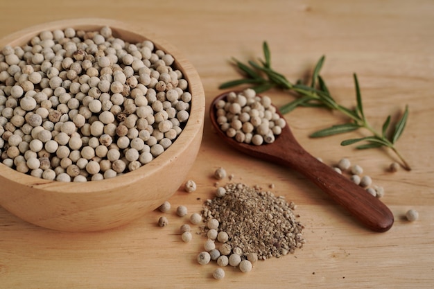 White pepper in a cup with wood grain background, industry concept