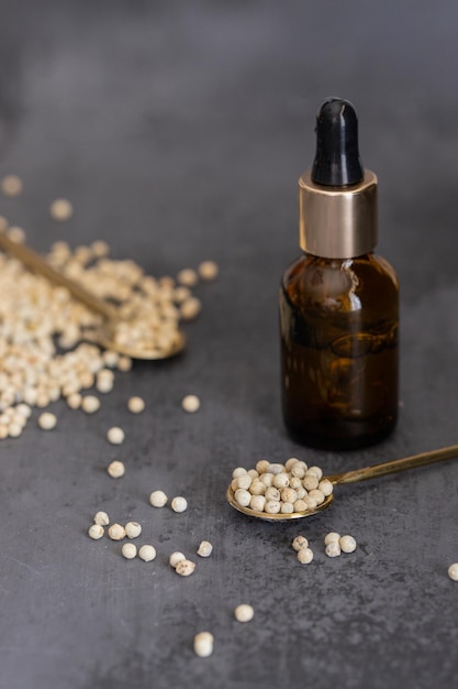 White pepper essential oil and white peppercorns on black background for beauty and natural medicine