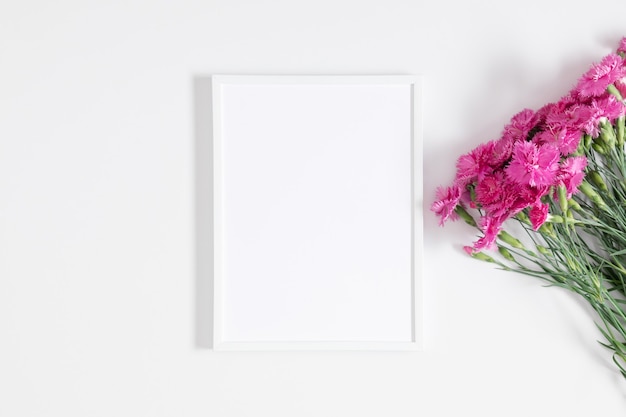 White photo frame and pink carnation flowers