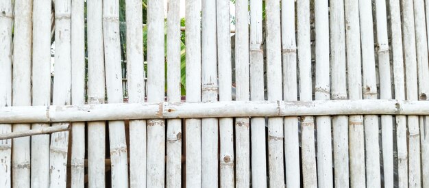 Photo a white picket fence with a wooden fence in the background