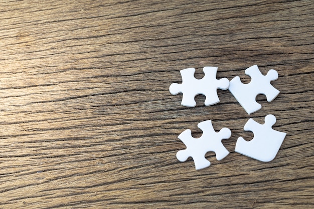 White pieces of puzzle lie on a wood table