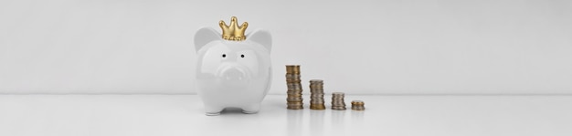 White piggi bank and stacks of coins on white background