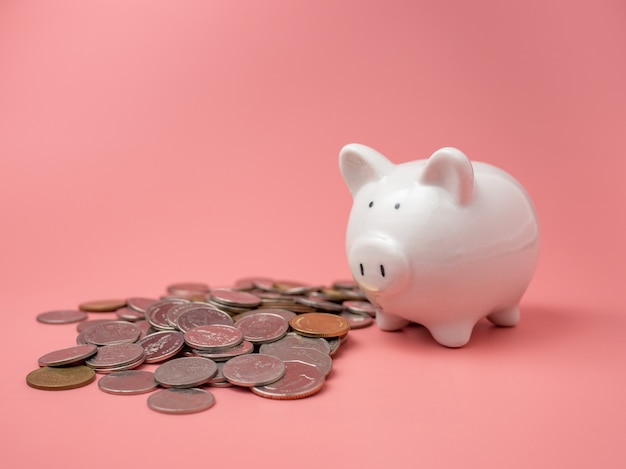 White piggy bank placed next to a pile of coins