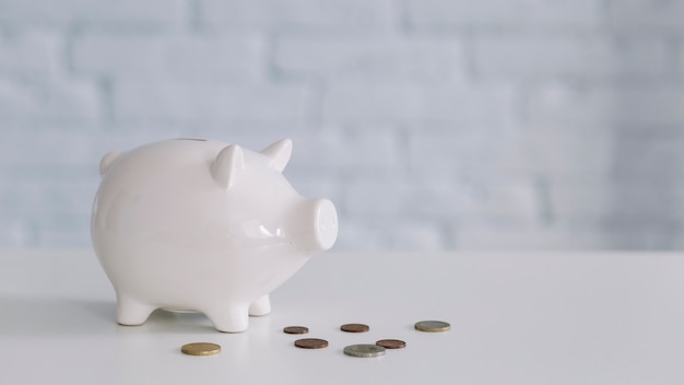 Photo white piggybank and coins on desk