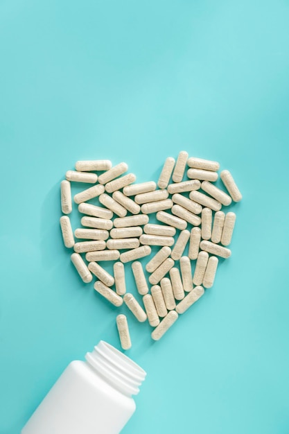 White pill bottles on blue background Heart desease treatment concept Food supplements vitamins and medicaments