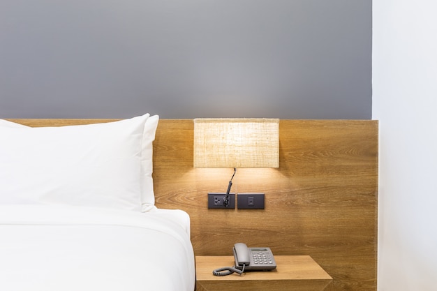 white pillow on bed decoration with light lamp and tissue box in hotel bedroom interior