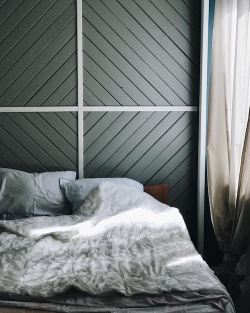 Photo white pillows and crumbled sheet on bed against wall at home