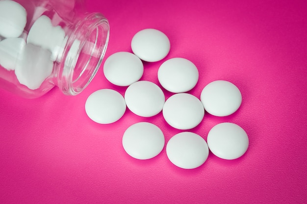 White pills are scattered from a glass bottle. Vignetting