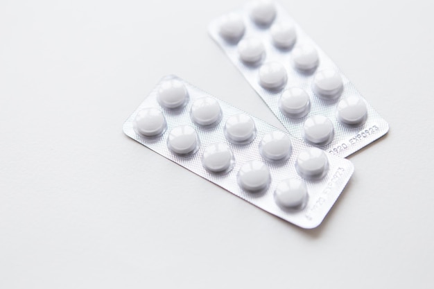 White pills in a blister pack isolated on a white background Place for an inscription The concept of health and medicine