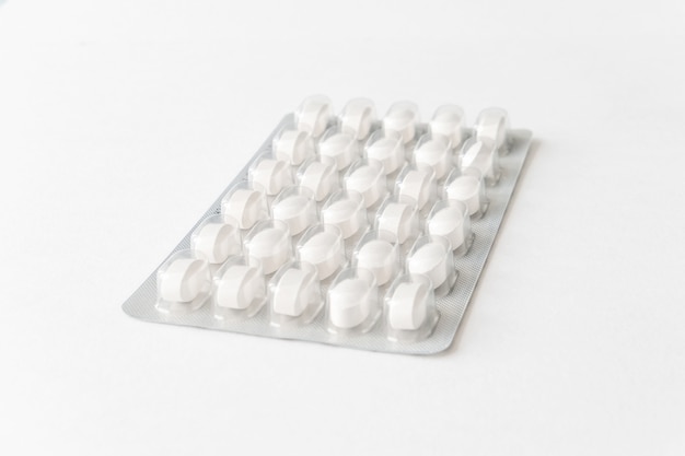 Белые таблетки в блистере на столе