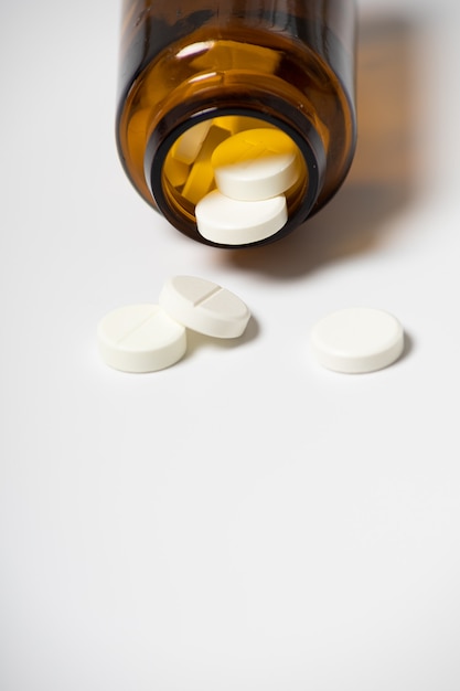 White pills from a jar on a white background