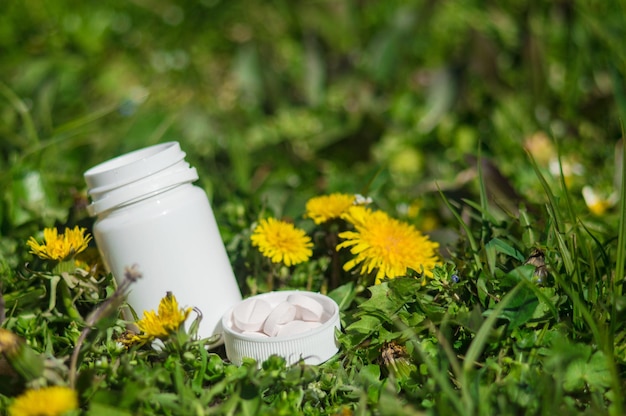 White pills in the grass with flowers Pills or tablets with dandelions closeup with bokeh Concept photo on theme Coronavirus and Covid19