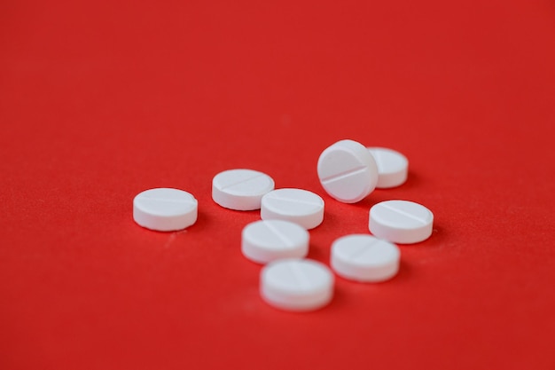 White pills isolated on red background