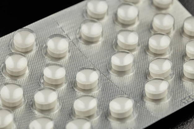 White pills isolated on a reflective black background