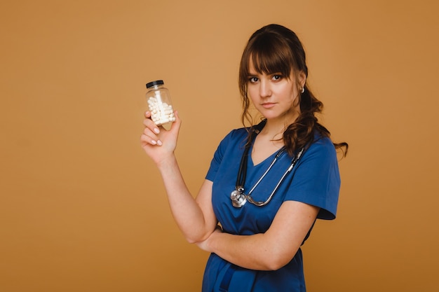 White pills in a jar of a female doctor. The doctor shows the vitamin capsules.