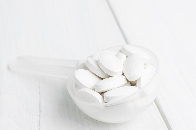 White pills in a plastic spoon, medication treatment, close-up view