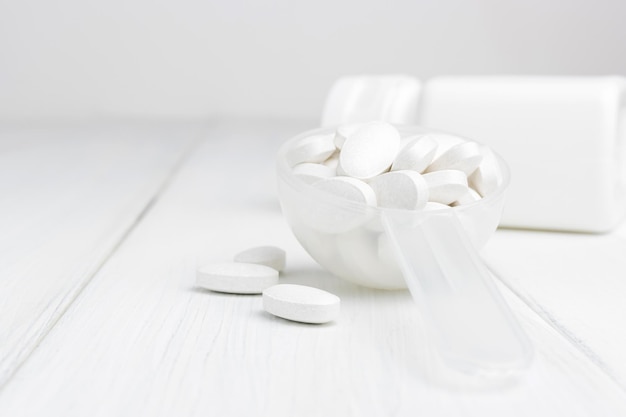 White pills in a plastic spoon, medication treatment, close-up view