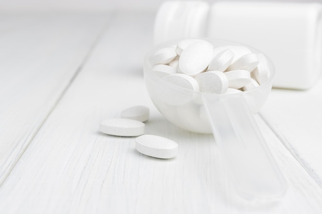 White pills in a plastic spoon, medication treatment, close-up view