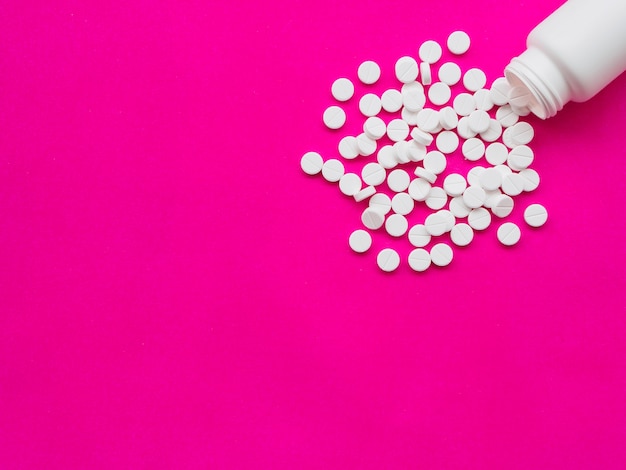 White pills spilling out of a white pill bottle