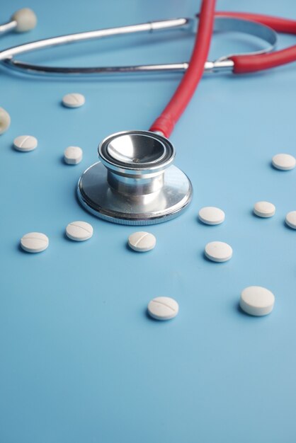 white pills and stethoscope on blue background