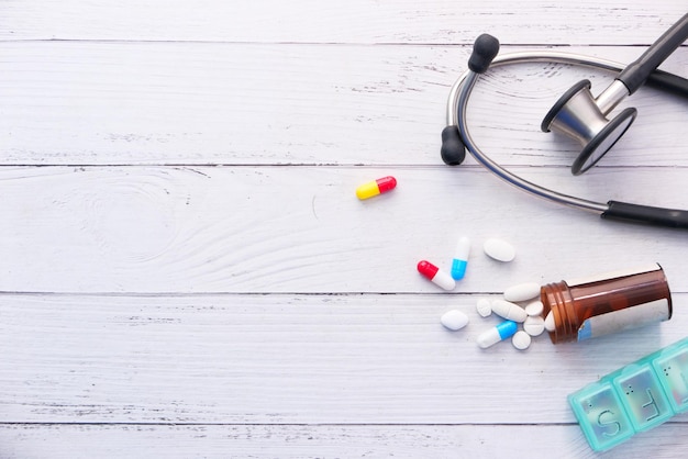 white pills and stethoscope on white background