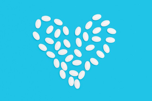 White pills for treatment in heart shape on blue background pharmacy and medicine concept top view