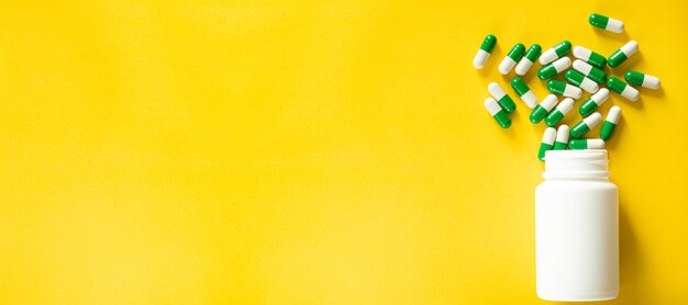 White pills and white bottle with copy space on yellow background Healthy and Medicine concept